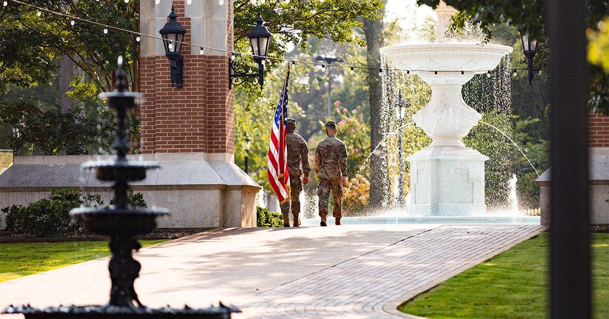 UNA ROTC members cross Harrison Plaza with the American Flag.